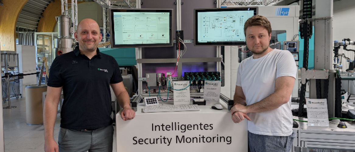 Zwei Teammitglieder aus dem Bereich Cybersicherheit stehen neben einem Technickdemonstrator.